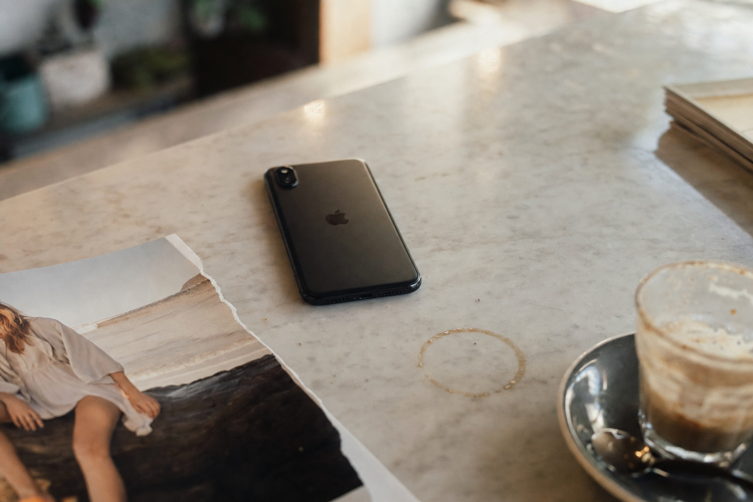 Smartphone showing a Meta ad creative with three printed mockups on a marble desk